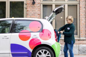 Kotihoidon työntekijä työautonsa takakontilla ottamassa tavaroita.